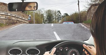 Over shoulder of driver, approaching brow of hill, day.