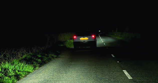 Car driving at night on quiet, poorly-lit road.