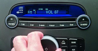 In-car entertainment controls, volume being adjusted by hand.
