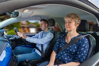 Female driving instructor with young male learner at the wheel