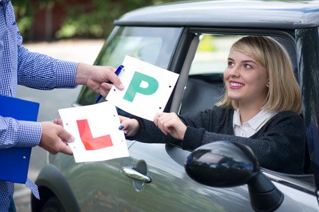 Learning driver exchanges L plate for P plate with instructor