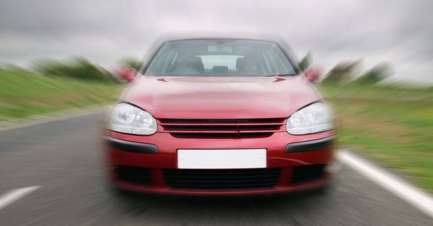 Car travelling toward camer with motion blur, day.