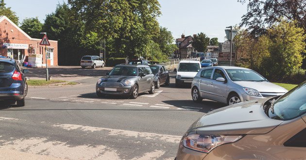 Traffic queueing at a busy junction, day.